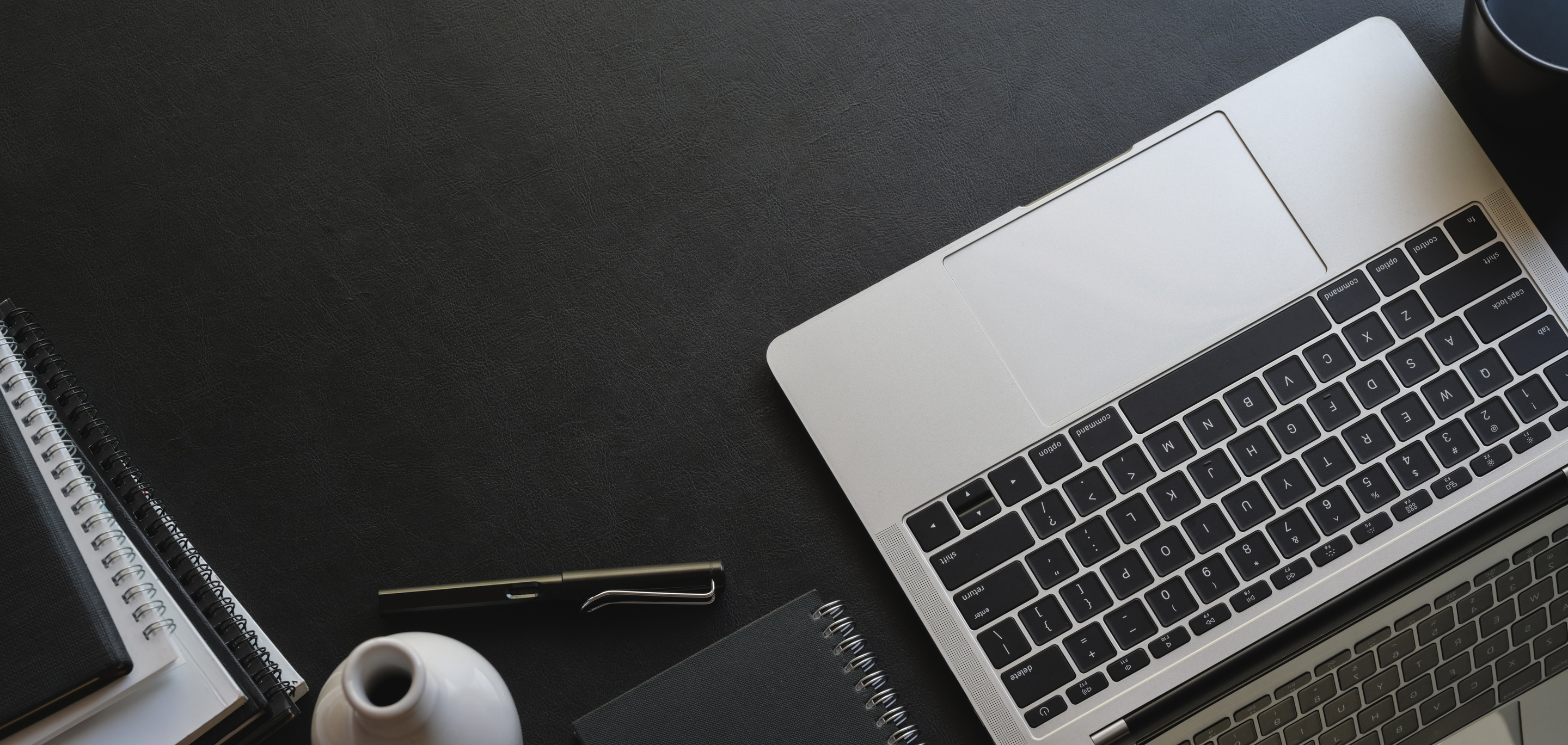 Black desk with laptop and stationery